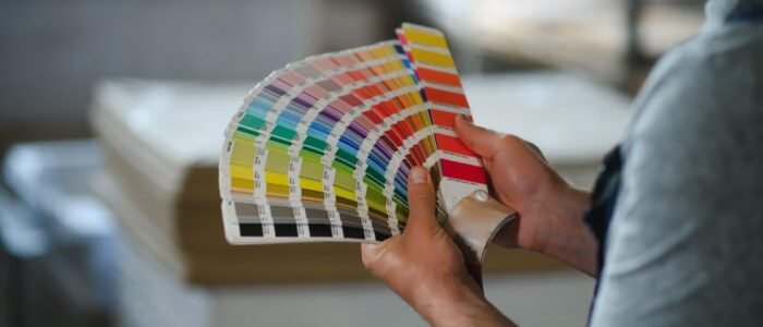 Man,Working,In,Printing,House,With,Paper,And,Paints.
